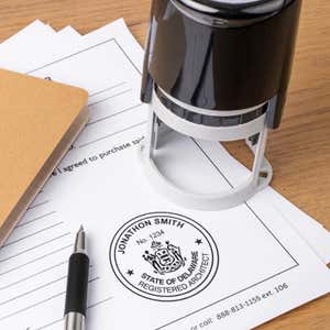 A self-inking stamp placed next to the State of Delaware Architect Seal at the bottom of a document