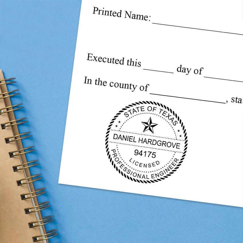 Texas engineer stamp impression on form with blue spiral notebook on light blue background.