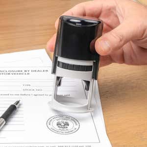 Notary tool in hand applying certification stamp on legal document surface