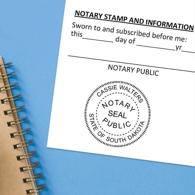 South Dakota notary stamp impression on white paper on a blue notebook. 