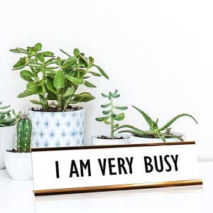 White desk plate with black custom text in rose gold holder on a desk