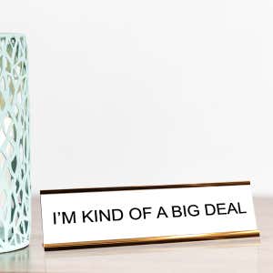 White desk plate with black custom text in a gold holder