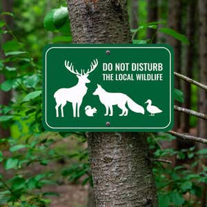 Forest green outdoor sign reads, Do Not Disturb the Local Wildlife, with images of a deer, fox, duck, and squirrel