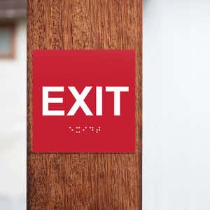 A red ADA exit sign on a pole