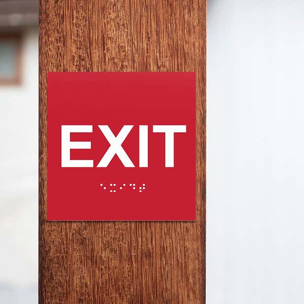 A red ADA exit sign on a pole