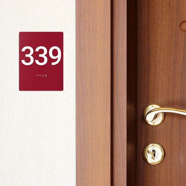 A red ADA sign with a room number