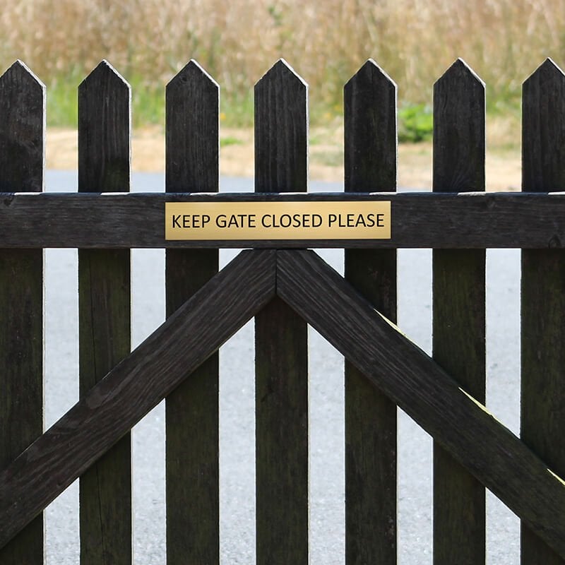 2x12 custom engraved brass sign on a fence