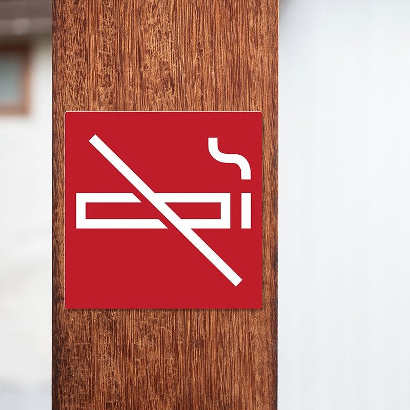 A red square engraved plastic sign with a no smoking symbol A red square engraved plastic sign with a no smoking symbol