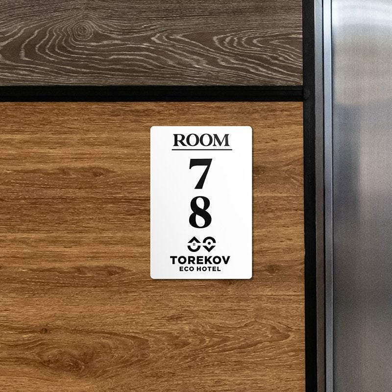 An engraved plastic sign with a room number and hotel logo An engraved plastic sign with a room number and hotel logo