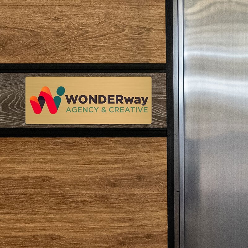 6x16 printed brass sign displayed on a wooden wall