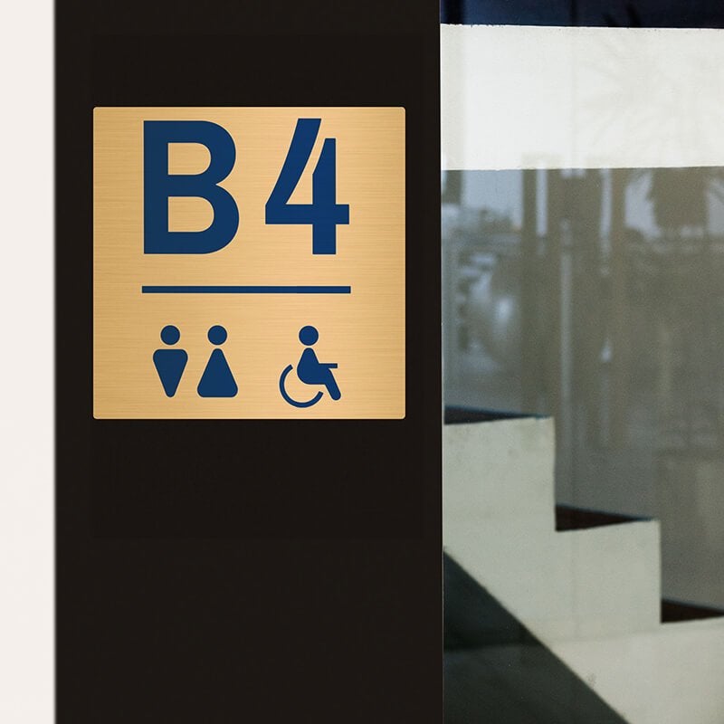 8x8 printed brass sign displayed next to an entrance