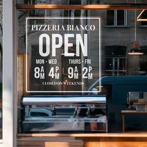 A clear window cling for a pizzeria with their store hours