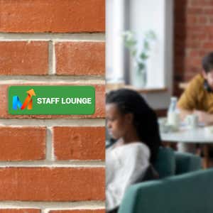 A Green Plastic Sign With a Company Logo and Says STAFF LOUNGE