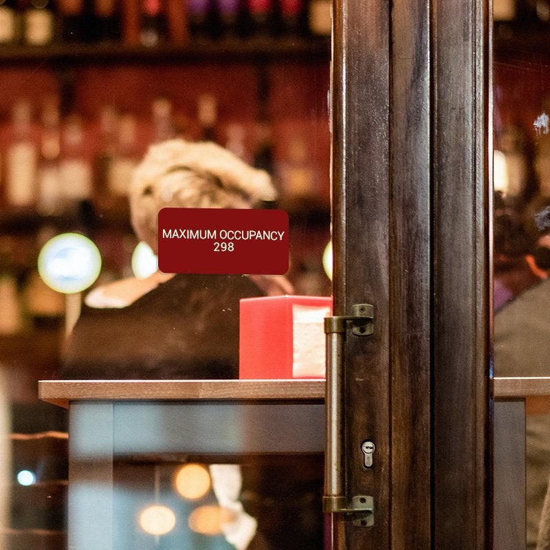 Red Plastic Sign With White Text Saying Maximum Occupancy 268