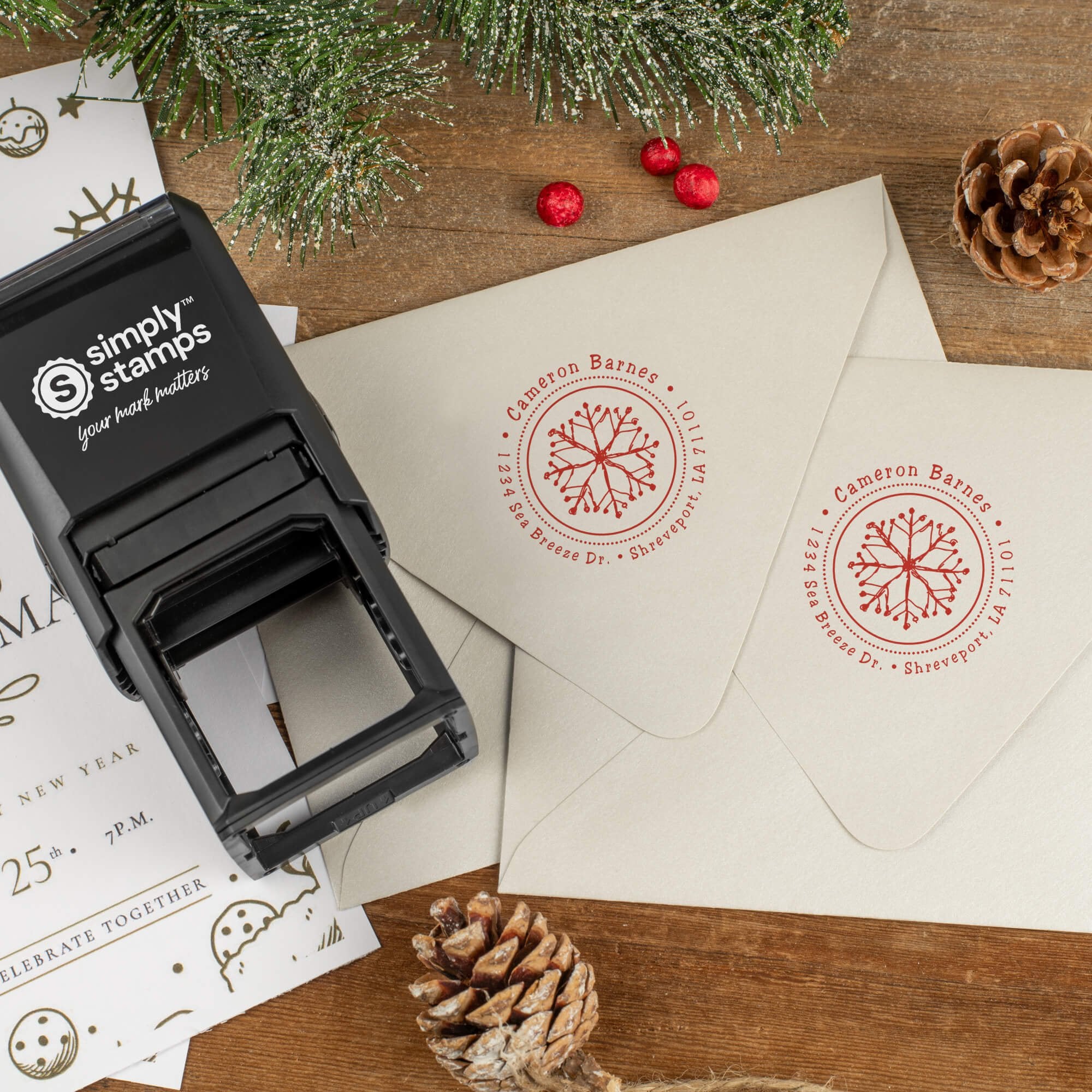 Holiday-themed ‘Hand Drawn Snowflake’ address stamp shown on envelopes beside festive stationery, pinecones, and decorations.